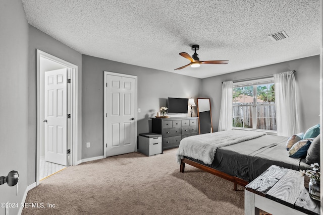 bedroom featuring a textured ceiling, light carpet, and ceiling fan