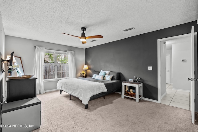 bedroom featuring a textured ceiling, light carpet, and ceiling fan