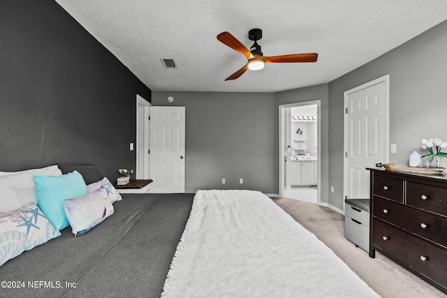 bedroom featuring a textured ceiling, light carpet, ceiling fan, and ensuite bathroom