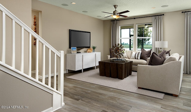 living room featuring a textured ceiling, wood-type flooring, and ceiling fan