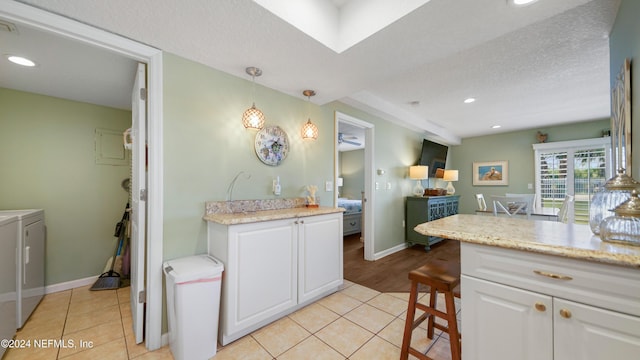 kitchen featuring pendant lighting, a kitchen breakfast bar, light tile patterned floors, separate washer and dryer, and white cabinetry