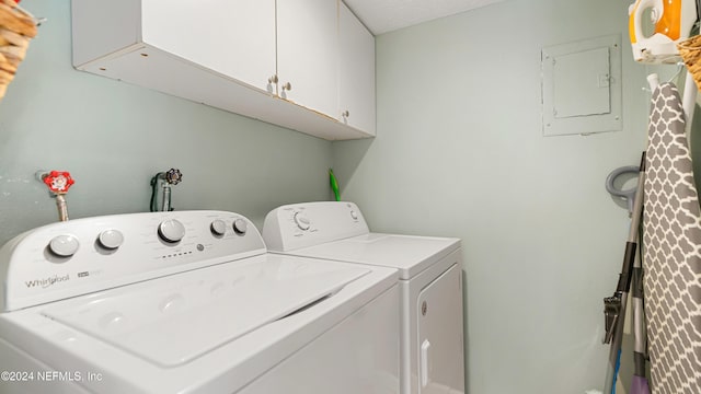 clothes washing area with cabinets, a textured ceiling, electric panel, and separate washer and dryer