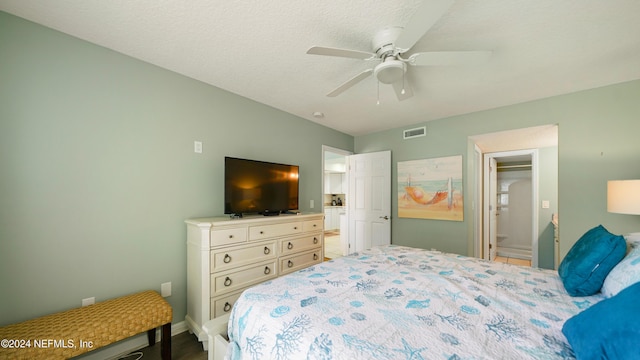 bedroom with a textured ceiling, connected bathroom, and ceiling fan