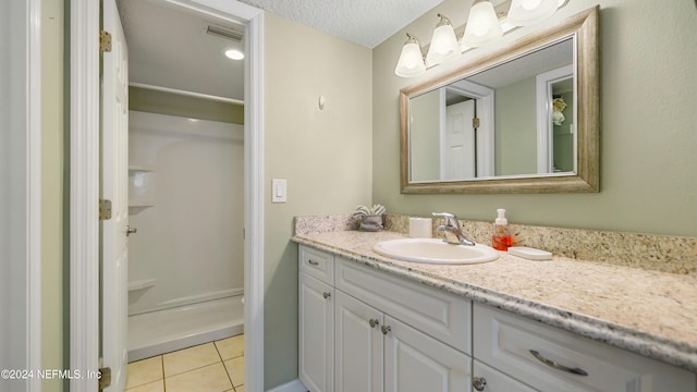 bathroom featuring a textured ceiling, vanity, tile patterned floors, and walk in shower