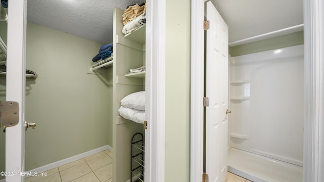 bathroom with tile patterned floors, a shower, and a textured ceiling