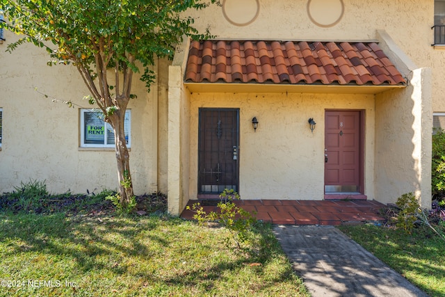 property entrance with a lawn