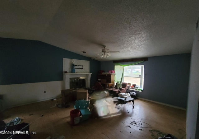 living room with hardwood / wood-style floors, ceiling fan, a textured ceiling, and lofted ceiling