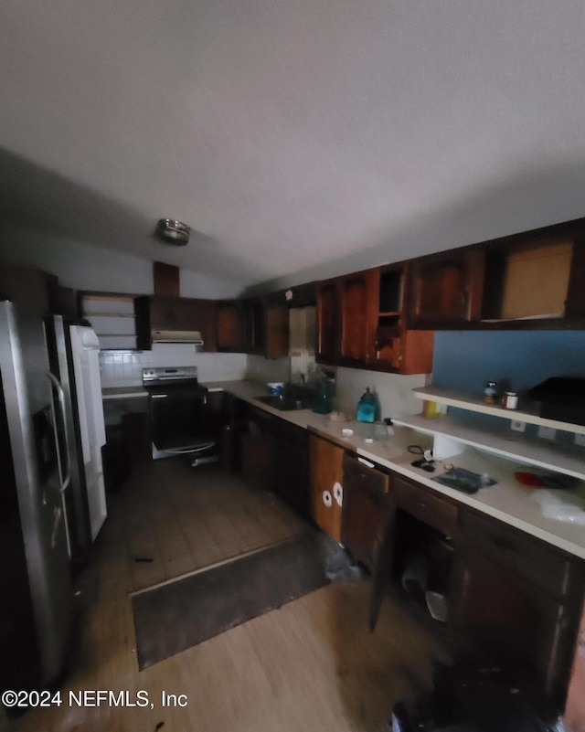 kitchen featuring cooktop, stainless steel refrigerator, dark hardwood / wood-style floors, lofted ceiling, and black / electric stove