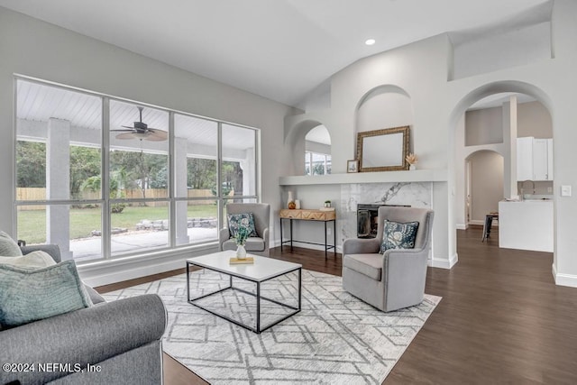 living room featuring hardwood / wood-style floors, ceiling fan, a high end fireplace, and vaulted ceiling