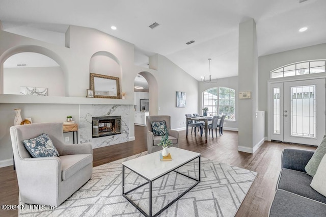 living room with a premium fireplace, an inviting chandelier, hardwood / wood-style flooring, and vaulted ceiling