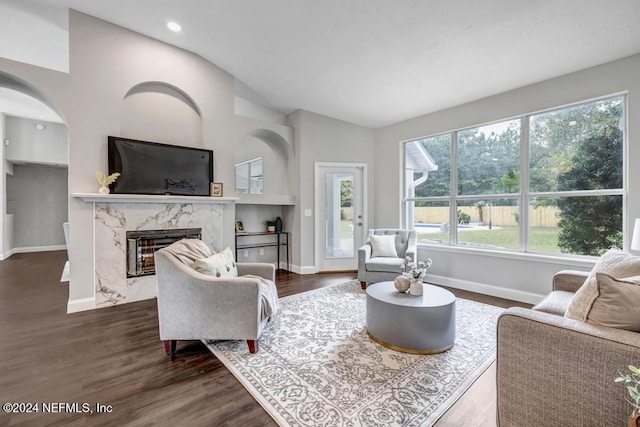 living room featuring lofted ceiling, a premium fireplace, a wealth of natural light, and dark hardwood / wood-style floors