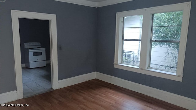 empty room with ornamental molding, a wealth of natural light, and hardwood / wood-style floors