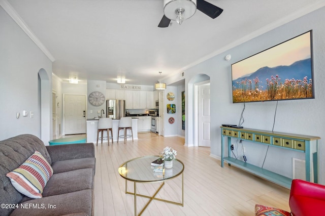 living room featuring crown molding, light hardwood / wood-style floors, and ceiling fan