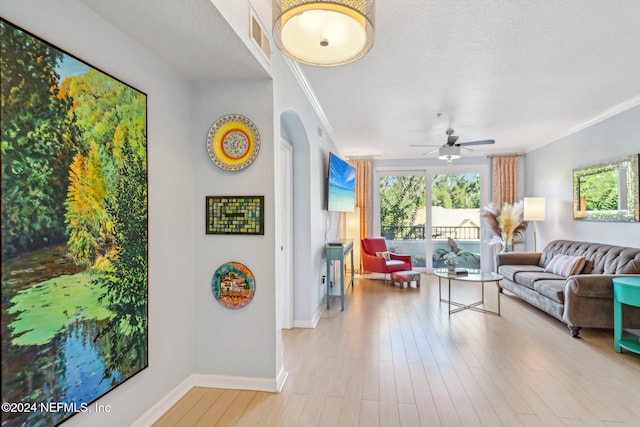 living room with light hardwood / wood-style floors, ornamental molding, and ceiling fan