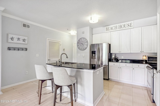 kitchen featuring appliances with stainless steel finishes, sink, an island with sink, and white cabinets