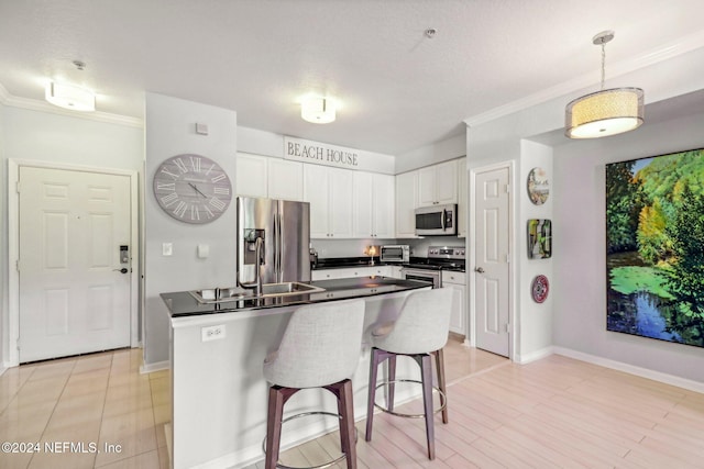 kitchen featuring a kitchen breakfast bar, white cabinetry, stainless steel appliances, decorative light fixtures, and ornamental molding