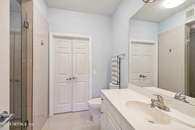 bathroom featuring vanity, toilet, walk in shower, and tile patterned flooring