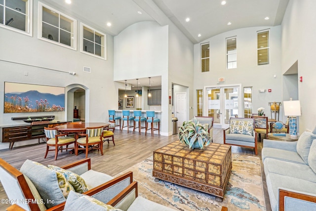 living room with light hardwood / wood-style flooring, beam ceiling, and high vaulted ceiling