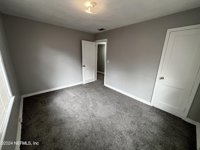 unfurnished bedroom with dark colored carpet