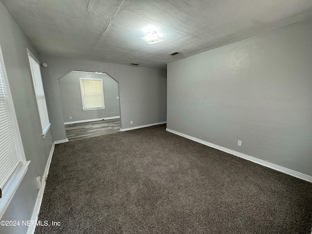 carpeted empty room with a textured ceiling