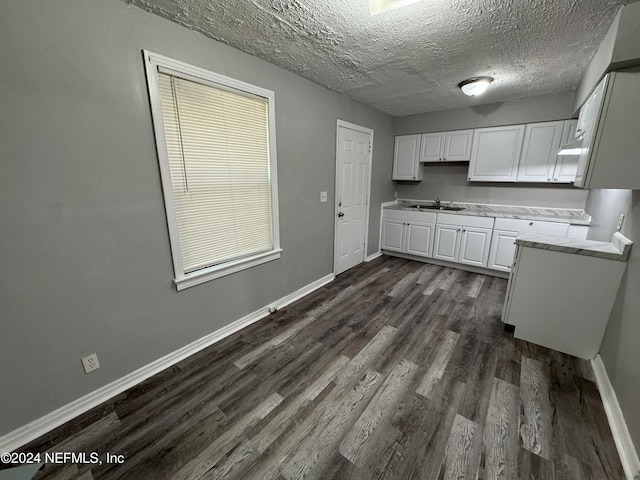 kitchen with sink, a textured ceiling, dark hardwood / wood-style flooring, white cabinetry, and a wealth of natural light