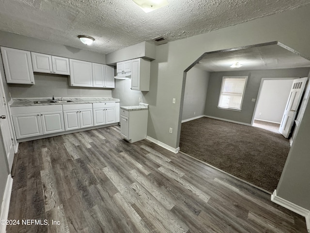 kitchen with white cabinets, sink, hardwood / wood-style floors, and a textured ceiling