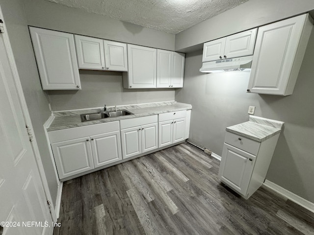 kitchen with white cabinetry, sink, wood-type flooring, and a textured ceiling