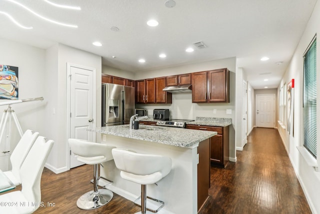 kitchen featuring appliances with stainless steel finishes, a kitchen bar, sink, an island with sink, and dark wood-type flooring