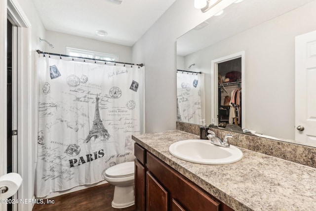 bathroom featuring hardwood / wood-style flooring, vanity, toilet, and walk in shower