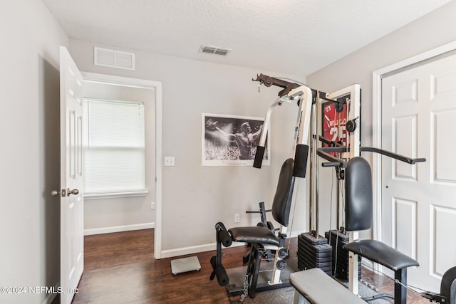 exercise area with a textured ceiling and dark hardwood / wood-style floors