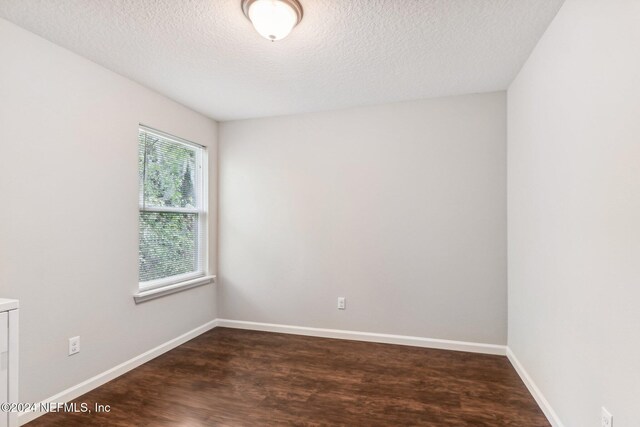 spare room featuring a textured ceiling and dark hardwood / wood-style flooring