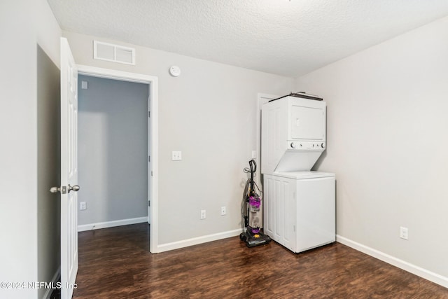 washroom featuring dark hardwood / wood-style flooring, stacked washing maching and dryer, and a textured ceiling