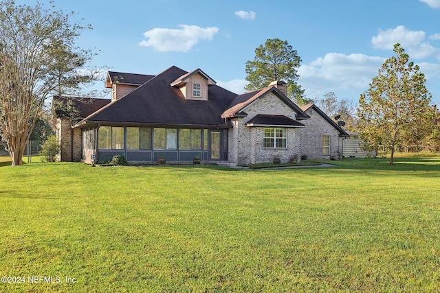 rear view of property featuring a sunroom and a lawn