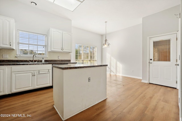 kitchen featuring sink, white cabinetry, decorative light fixtures, and light wood-type flooring