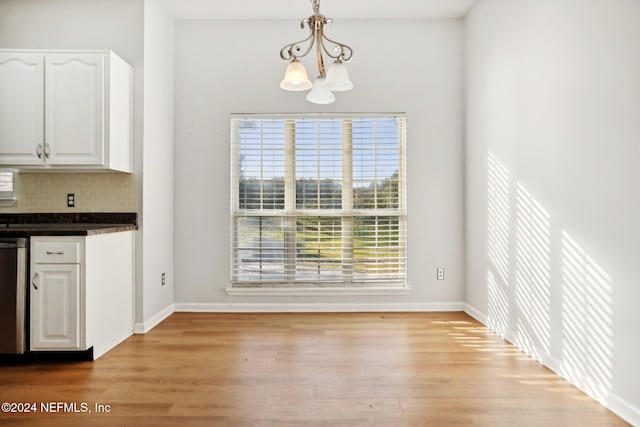 unfurnished dining area featuring a notable chandelier and light wood-type flooring