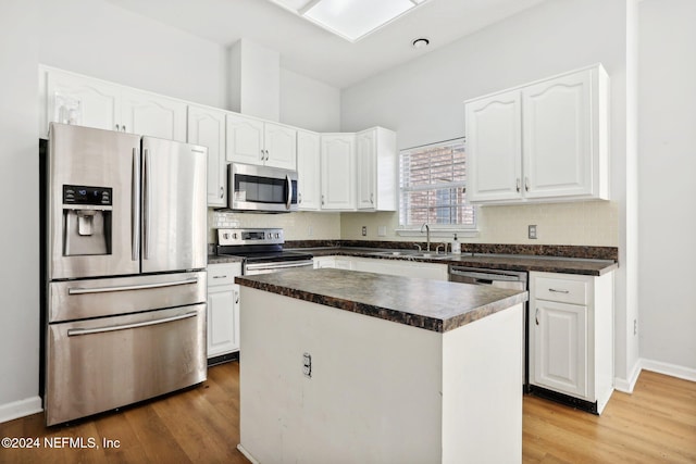 kitchen featuring a kitchen island, stainless steel appliances, hardwood / wood-style floors, sink, and white cabinets