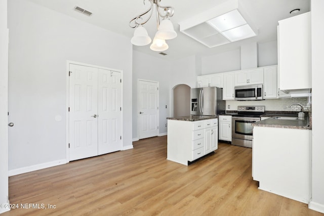 kitchen featuring white cabinets, appliances with stainless steel finishes, sink, light hardwood / wood-style floors, and decorative light fixtures