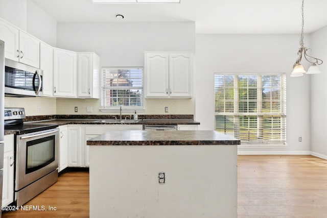 kitchen featuring appliances with stainless steel finishes, a center island, hanging light fixtures, white cabinets, and light hardwood / wood-style flooring