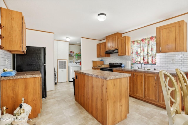 kitchen with backsplash, a kitchen island, ornamental molding, black appliances, and washing machine and dryer