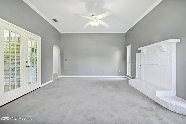 unfurnished living room featuring carpet flooring, french doors, a brick fireplace, ceiling fan, and ornamental molding