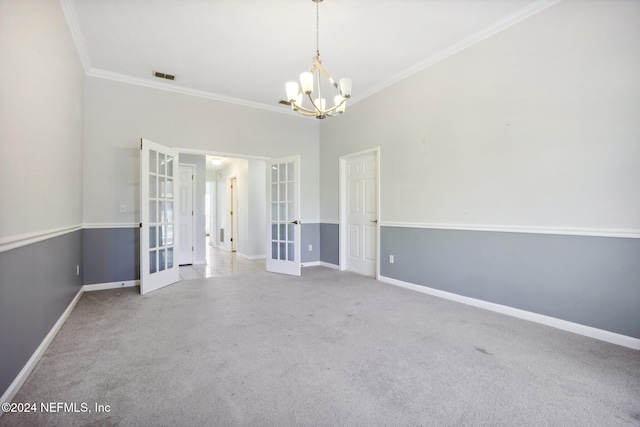 carpeted spare room with french doors, crown molding, and an inviting chandelier