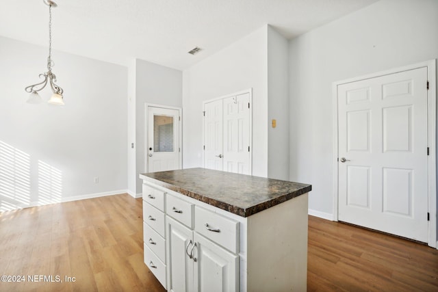 kitchen featuring white cabinetry, light hardwood / wood-style flooring, decorative light fixtures, and a center island