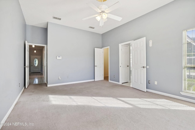 unfurnished bedroom featuring multiple windows, light colored carpet, and ceiling fan