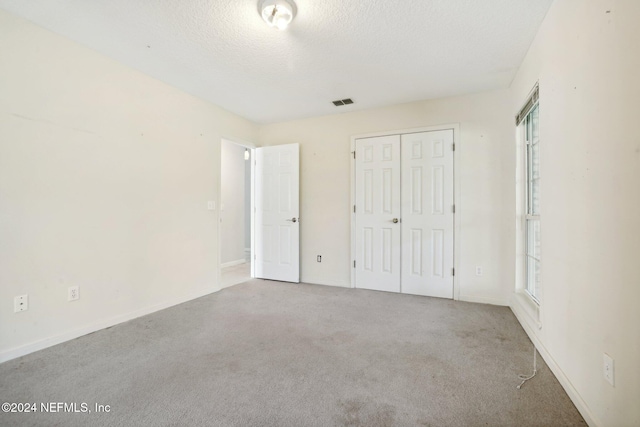 unfurnished bedroom with a closet, light carpet, and a textured ceiling