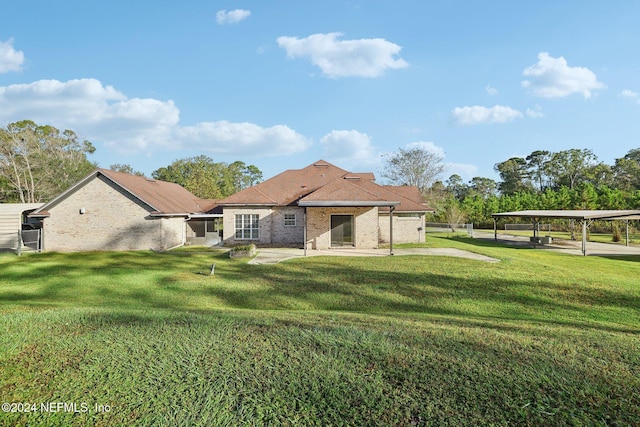 rear view of property with a lawn and a carport