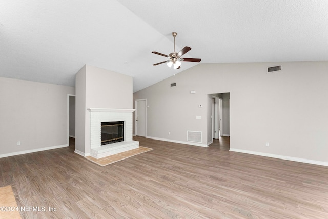 unfurnished living room featuring high vaulted ceiling, a brick fireplace, ceiling fan, and light hardwood / wood-style flooring