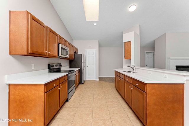 kitchen with kitchen peninsula, sink, light tile patterned flooring, and stainless steel appliances