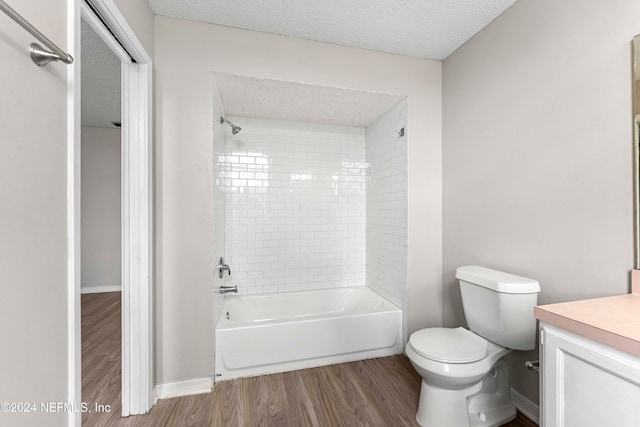 full bathroom with toilet, tiled shower / bath, a textured ceiling, hardwood / wood-style flooring, and vanity