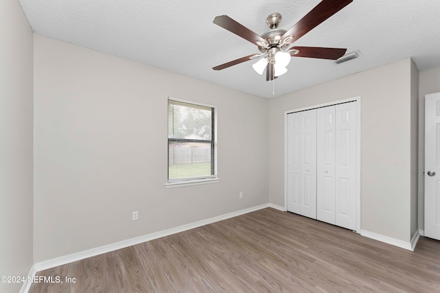 unfurnished bedroom with a closet, ceiling fan, a textured ceiling, and light hardwood / wood-style floors