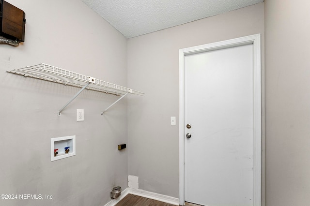 clothes washing area featuring hardwood / wood-style floors, washer hookup, and a textured ceiling